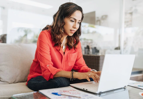 Person sitting at sofa typing on laptop