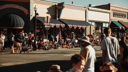 An image of a busy street with shops and buildings and various people.