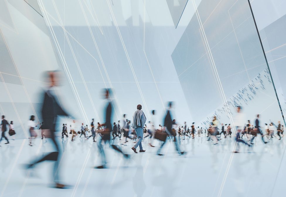 An image of multiple motion blurred business people walking inside of a white building with white lines overlaying the image.