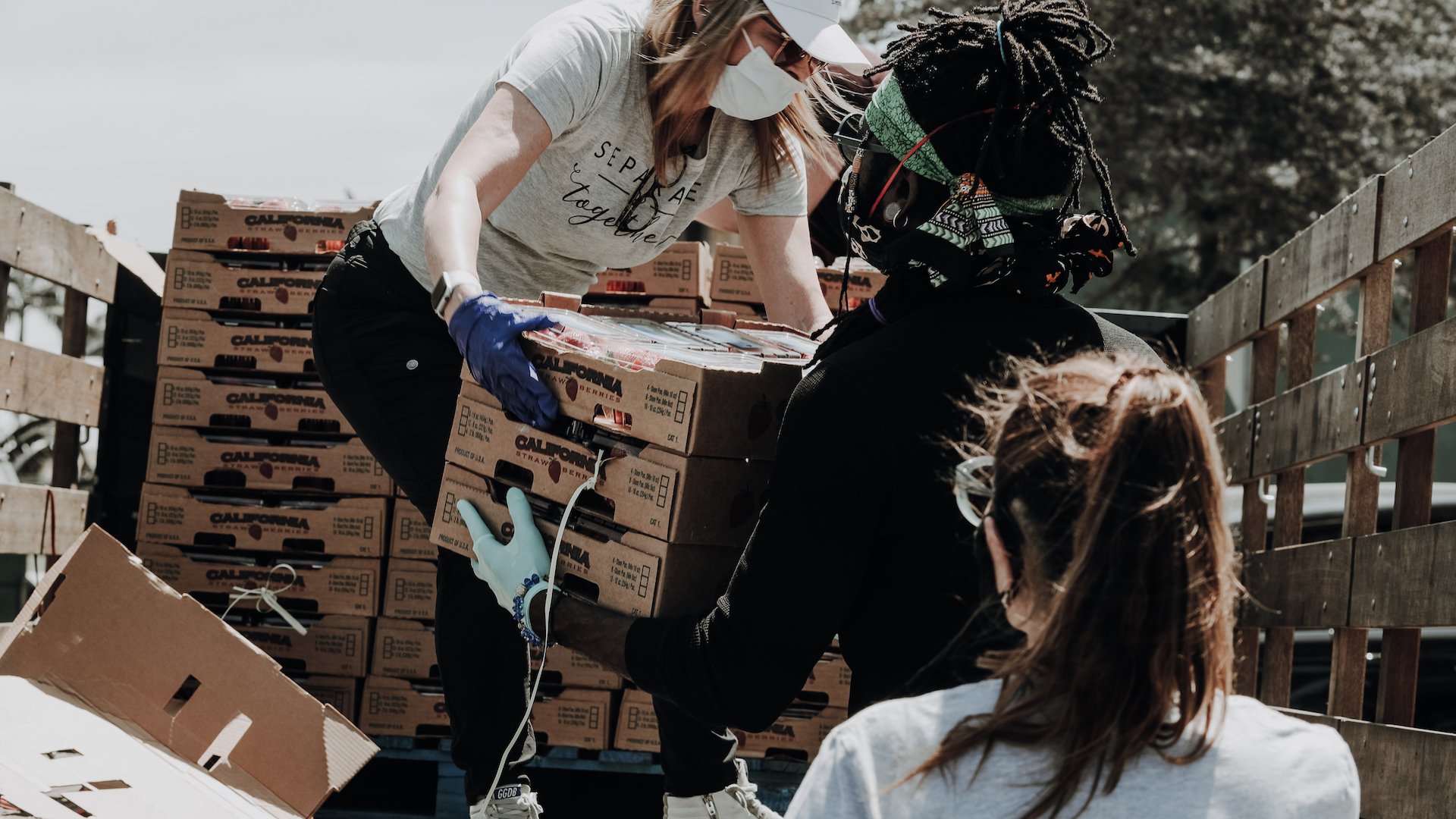 women in masks volunteering and unloading boxes from truck 