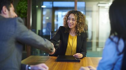 woman in a board room shaking someone's hand