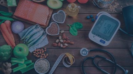 Fish, produce and a blood pressure monitor on a wooden surface