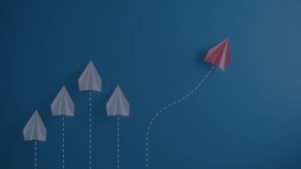 three white paper planes and a red one