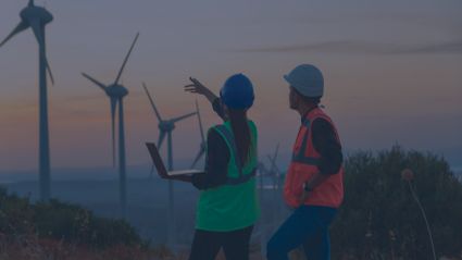 Two workers observe wind turbines