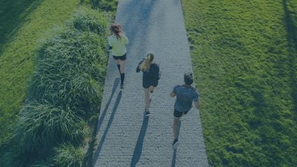 three people jogging on a paved trail