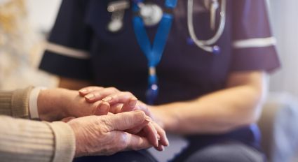 A nurse holds a patient's hands