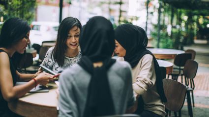 Four women sit around a table in conversation