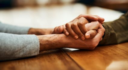 Two individuals with their hands grasped across a table