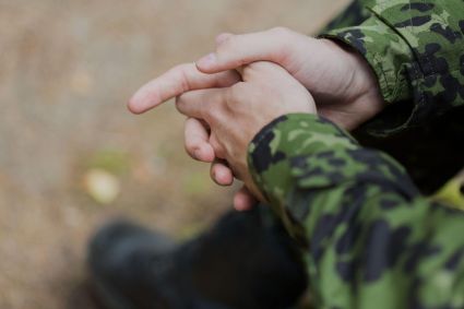 A person holding their hands wearing a green camo long-sleeved shirt