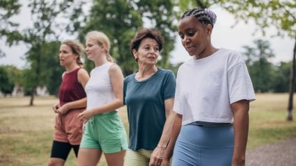 four people walking together in a park during the day