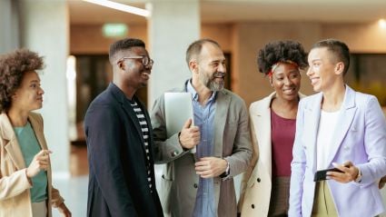 A group of people in an office setting laugh and talk