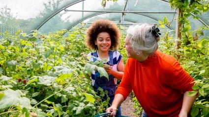 A young woman and older woman work in a greenhouse together