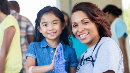 A young girl and a woman place their palms together.