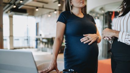 pregnant woman standing by a table with hand on her belly