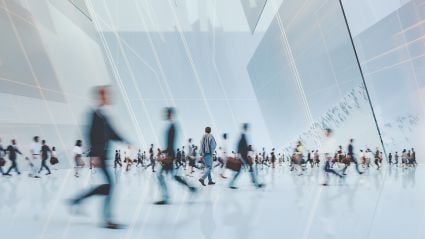 An image of multiple motion blurred business people walking inside of a white building with white lines overlaying the image.