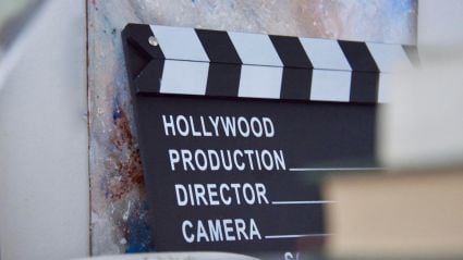 An up close image of a clapperboard which has the words "Hollywood", "Production", "Director", and "Camera". The image is a header image leading to an article from the Milken Institute about the challenges in funding streams and financing facing the entertainment industry.