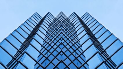 Upward view of a tall glass building with symmetrical repeating window patterns.