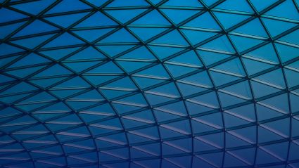 Geometric glass roof with triangular grid pattern in blue gradient light.