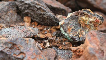 Close-up view of raw mineral rocks with rough, textured surfaces in shades of brown, orange, gray, and green.