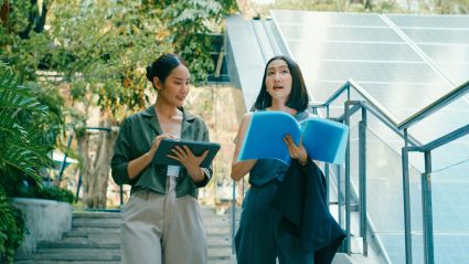 Two colleagues review documents in front of solar panels, highlighting collaboration in clean energy innovation.