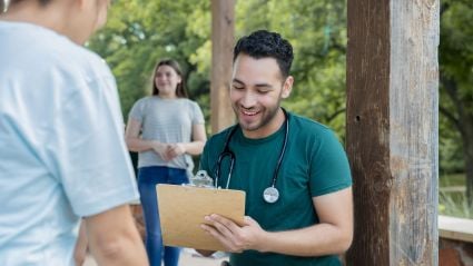 Delivery person in green shirt handing package to customer at doorstep