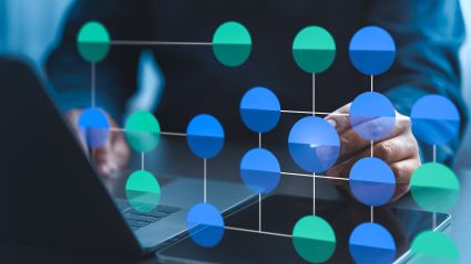 A person working on a laptop with a digital overlay of a connected network of blue and green nodes, representing data or blockchain technology.