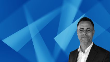 Professional headshot of businessman in suit against blue geometric background