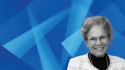 Professional woman in white blazer smiling against blue geometric background