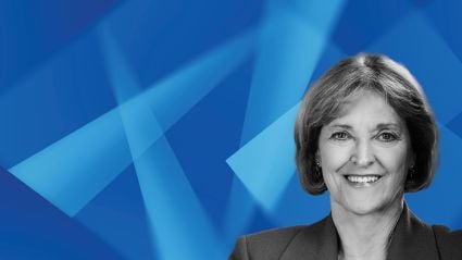 Professional headshot of smiling woman against blue geometric background