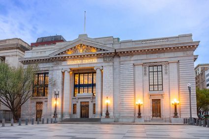 Milken Center in Washington, DC, a classical white stone building with illuminated columns at dusk