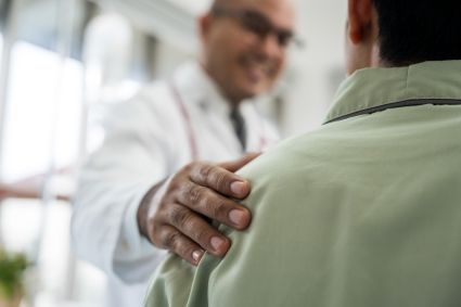Doctor in white coat with hand on patient's shoulder