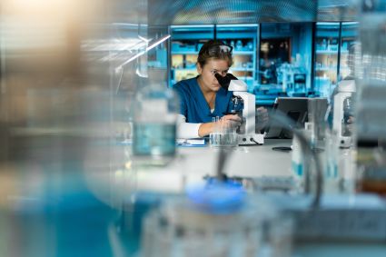 Scientist at a computer in laboratory with blue lighting