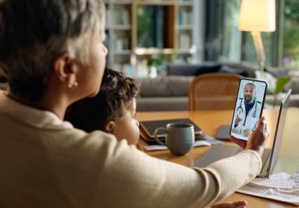 Woman video calling with a doctor with child on her lap