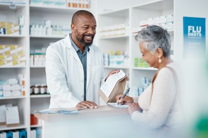 Pharmacist consulting with elderly female patient at pharmacy counter