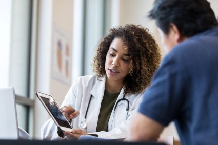 Healthcare worker consulting with patient at a desk with a tablet