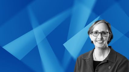 Professional headshot of a smiling woman with glasses against a blue geometric background