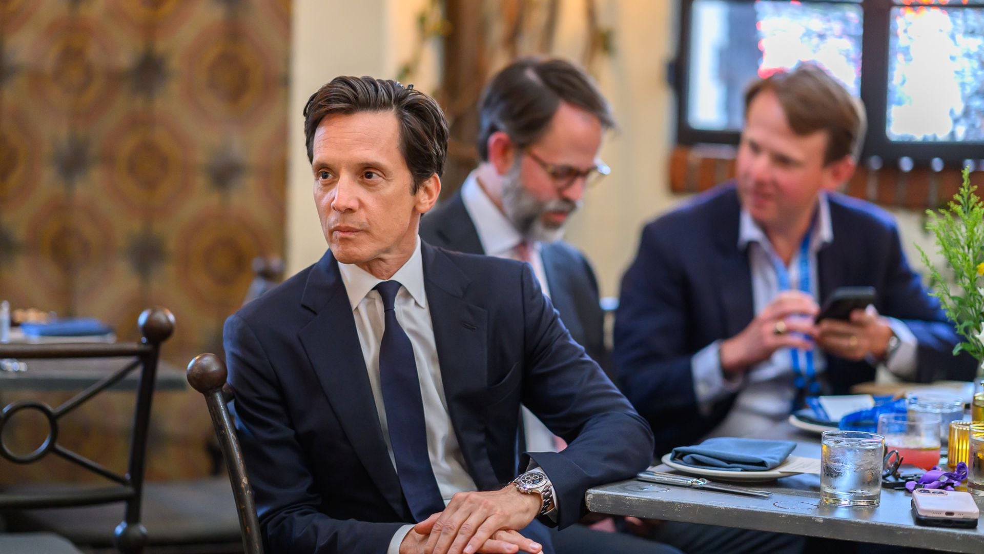 Three businessmen in suits sitting at a conference table during a meeting