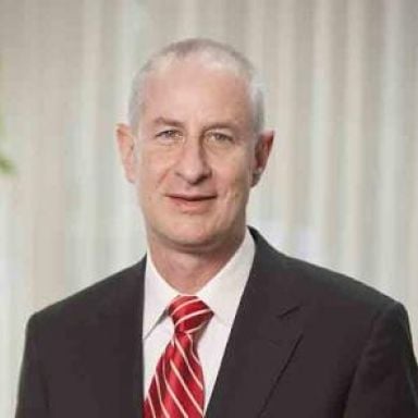 A male-presenting person wearing a tie against a blurred background.