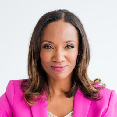A confident woman with long brown hair wearing a bright pink blazer and cream lace top, smiling slightly against a plain white background