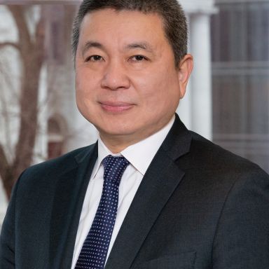Professional headshot of an Asian businessman in a dark suit and tie