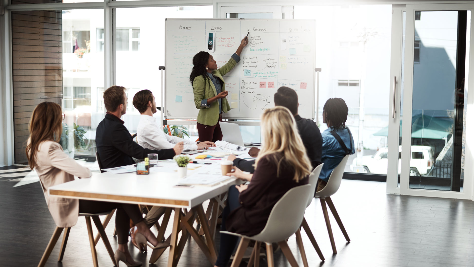 Business team meeting around conference table in modern office with large windows.