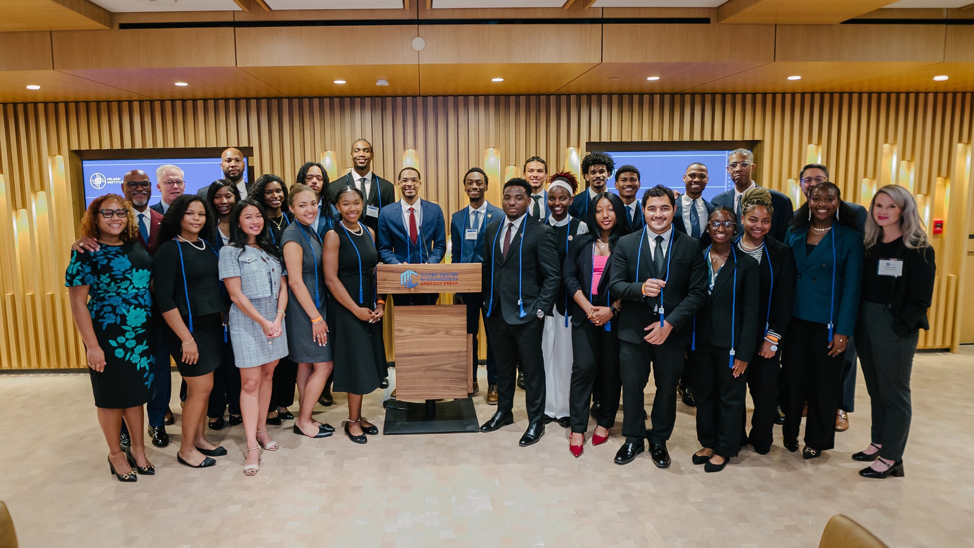 Large diverse group of professionals posing together in a modern conference room with wood paneling