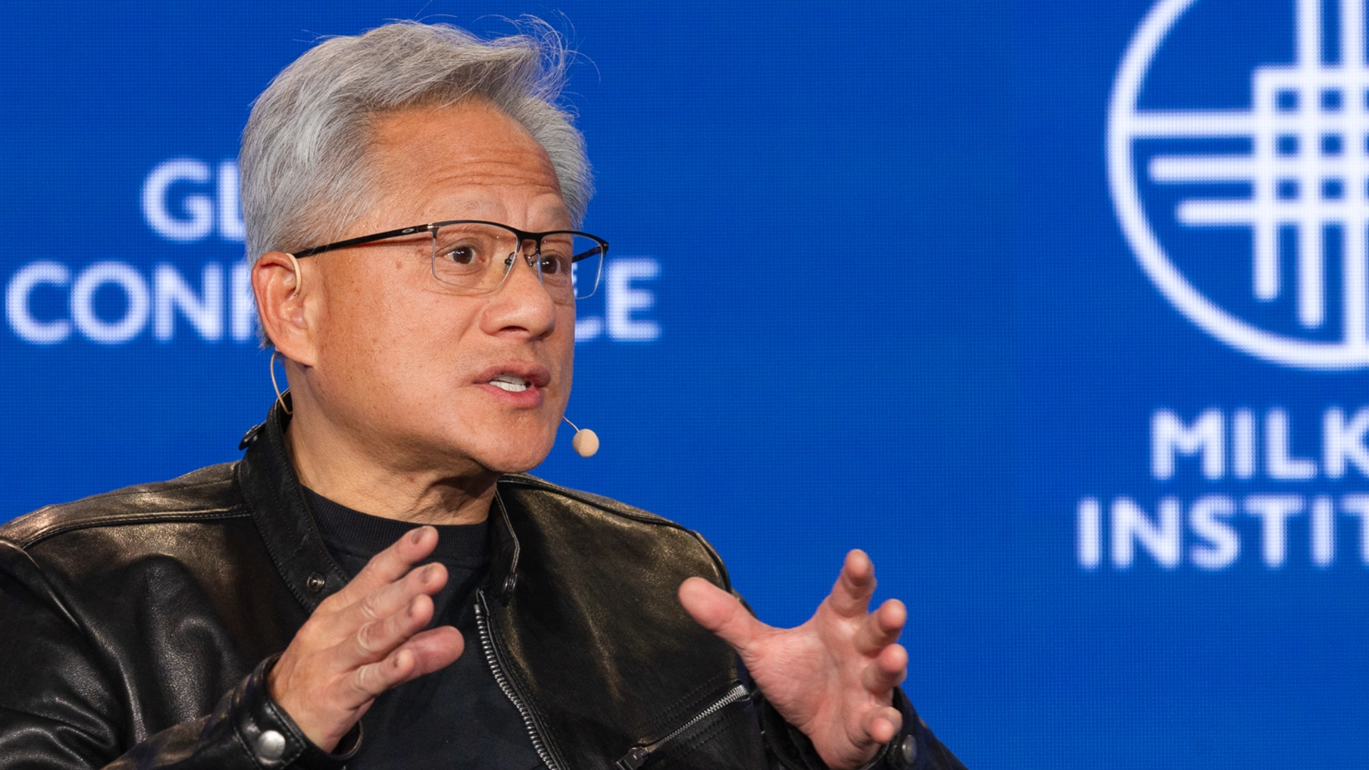 Jensen Huang speaking at Milken Institute event with blue background
