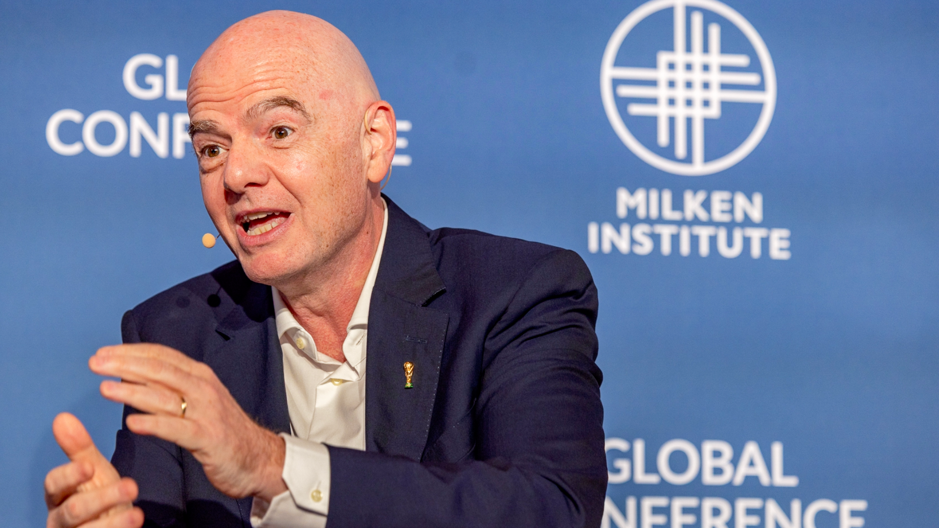 Gianni Infantino in navy suit gesturing while speaking at Global Conference panel