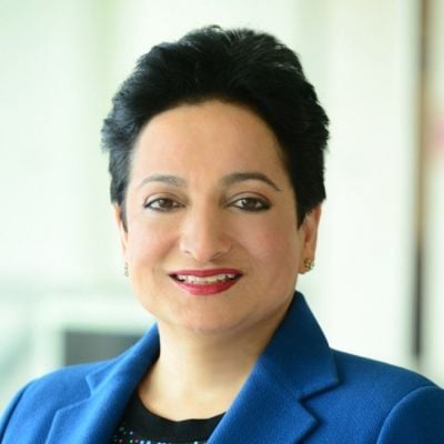 A smiling female-presenting person of Asian heritage with short black hair wearing a bright blue suit jacket against a blurred background