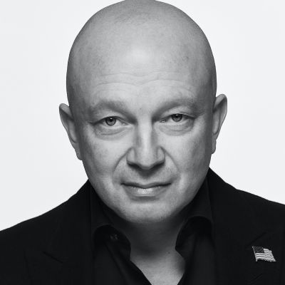 A male-presenting person wearing a dark shirt against a light background with a grayscale filter applied