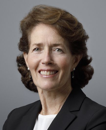 Image of Carol Geremia with medium-length brown hair in a white top and dark blazer smiles at the camera