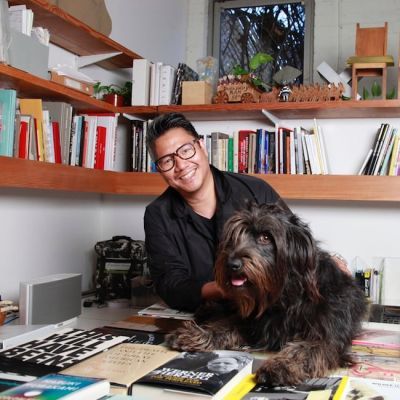 A smiling male sitting in an office with his dog on his lap