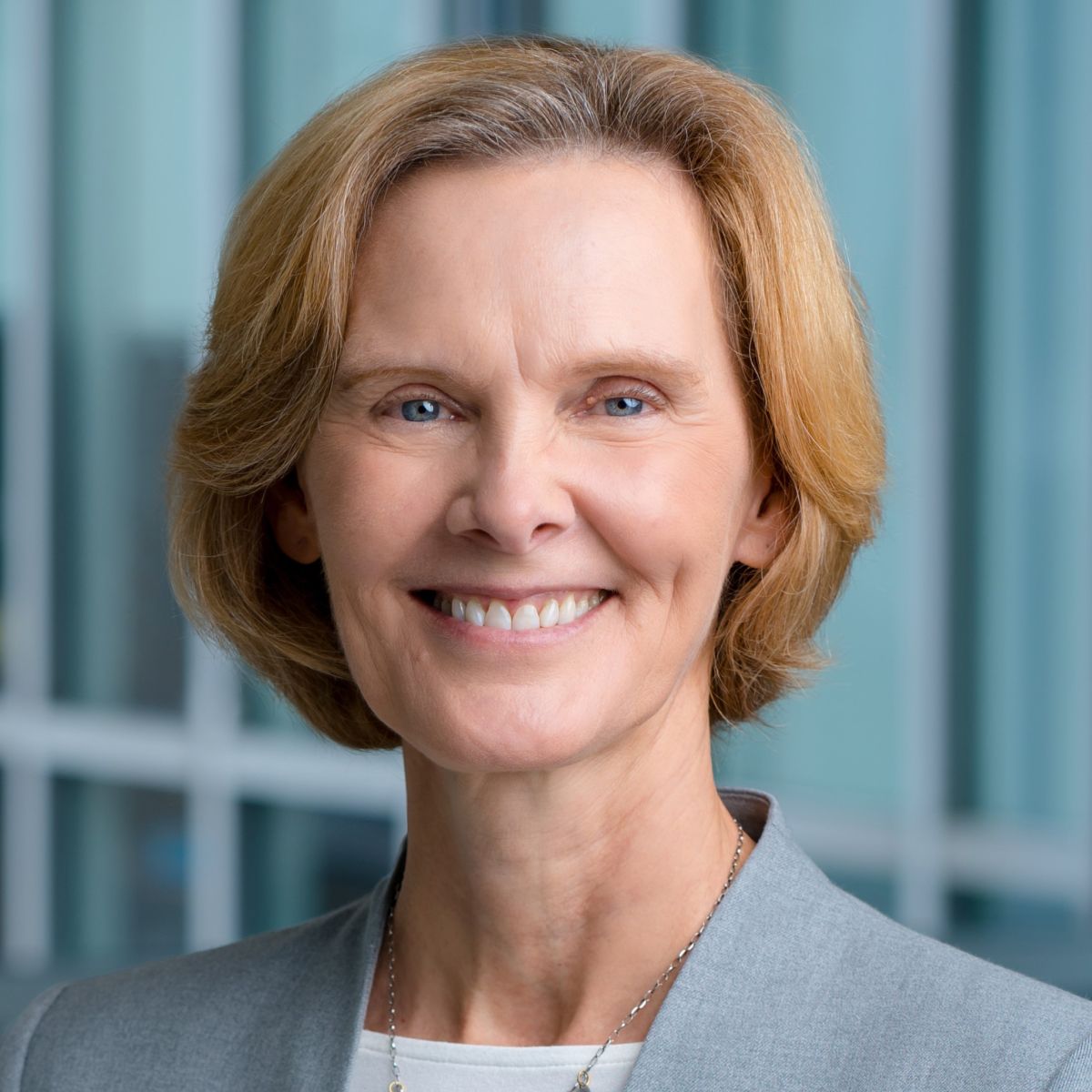 Professional smiling woman against a glass backdrop.