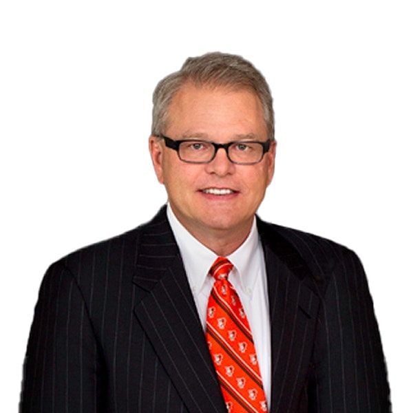 A smiling light-skinned male with gray hair wearing a suit and tie and glasses against a white background